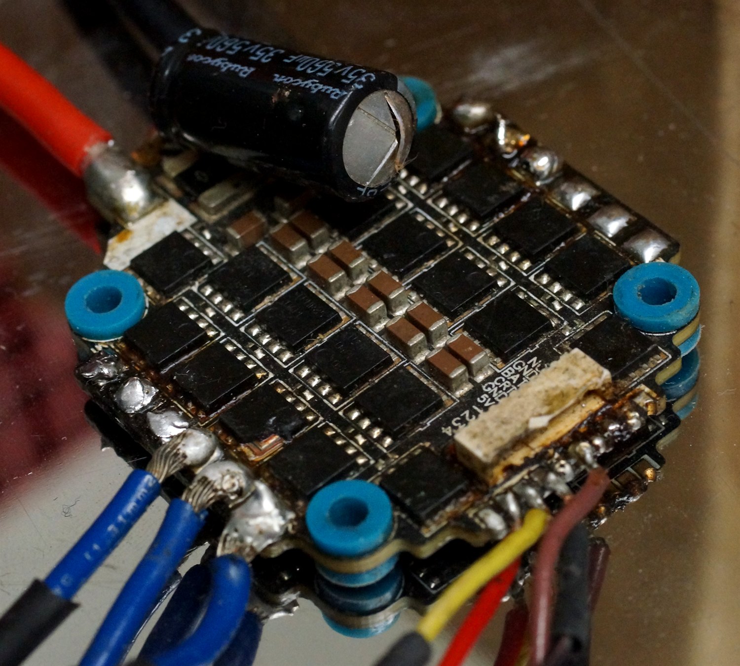 Placa de un controlador electrónico con un condensador hinchado y una zona quemada junto a los componentes, por sobrecalentamiento